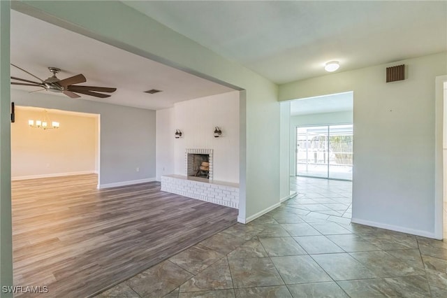 4330 S Canal Cir, North Fort Myers, FL 33903 - unfurnished living room with a brick fireplace, baseboards, ceiling fan, a chandelier, and wood finished floors