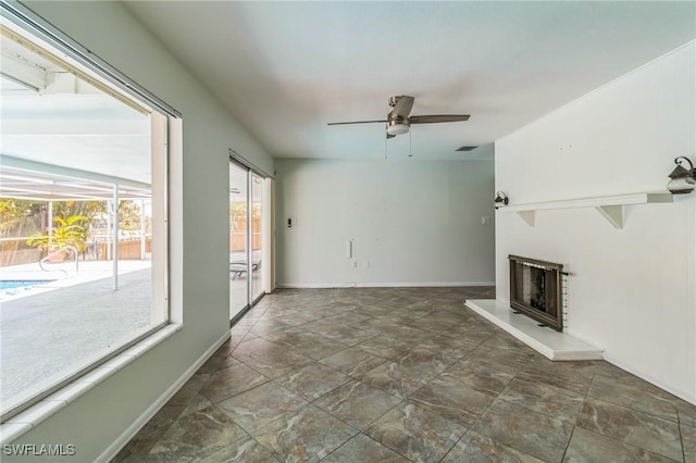 4330 S Canal Cir, North Fort Myers, FL 33903 - unfurnished living room with ceiling fan, a fireplace with raised hearth, stone finish flooring, and baseboards