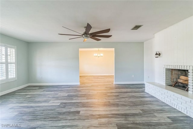 4330 S Canal Cir, North Fort Myers, FL 33903 - unfurnished living room featuring a fireplace, a ceiling fan, wood finished floors, baseboards, and a chandelier