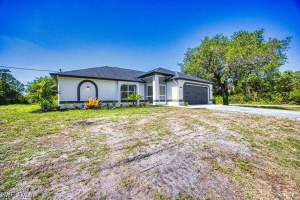 3815 Kittyhawk Dr, Fort Myers, FL 33905 - view of front of property with driveway, an attached garage, stucco siding, and a front lawn