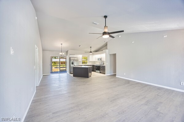 3815 Kittyhawk Dr, Fort Myers, FL 33905 - unfurnished living room featuring a ceiling fan, baseboards, light wood-style flooring, high vaulted ceiling, and a chandelier