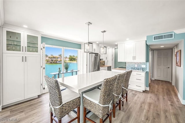 333 Harbour Dr Unit 201, Naples, FL 34103 - kitchen with high end refrigerator, light wood-type flooring, recessed lighting, decorative backsplash, and white cabinets