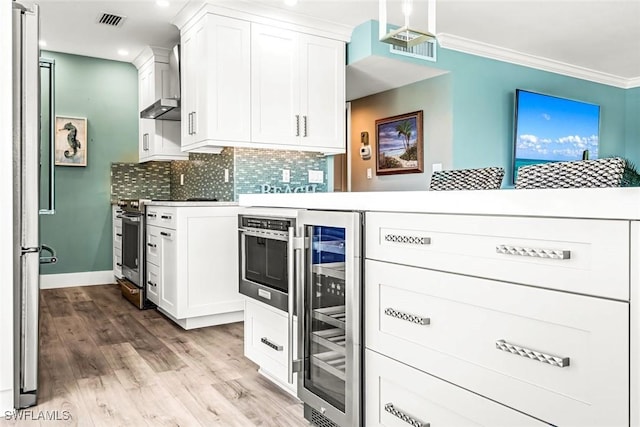 333 Harbour Dr Unit 201, Naples, FL 34103 - kitchen with beverage cooler, wall chimney exhaust hood, light wood-style flooring, backsplash, and light countertops