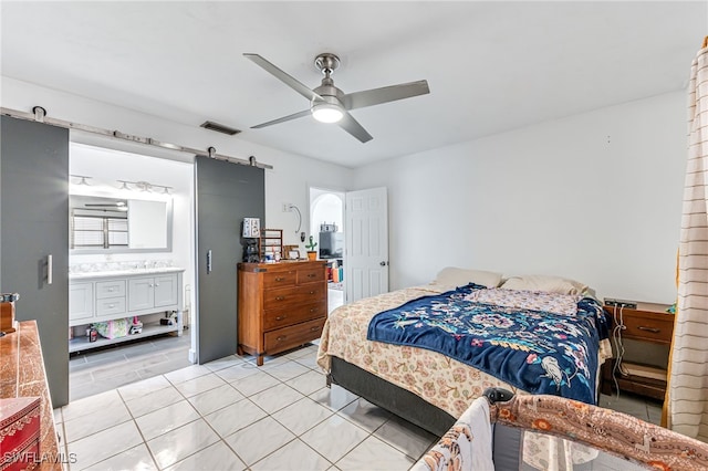 626 103rd Ave N, Naples, FL 34108 - bedroom featuring a barn door, light tile patterned flooring, connected bathroom, ceiling fan, and a sink