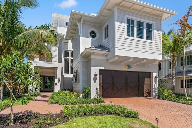 217 13th St S, Naples, FL 34102 - view of front of home with a garage, decorative driveway, a standing seam roof, and stucco siding