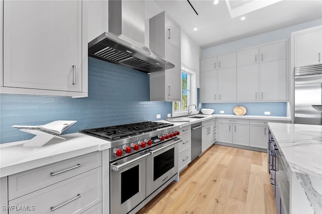 217 13th St S, Naples, FL 34102 - kitchen featuring wall chimney exhaust hood, high quality appliances, light wood-style flooring, recessed lighting, and backsplash
