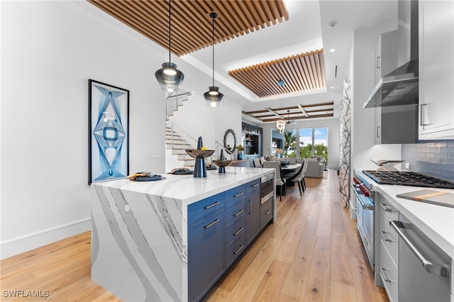 217 13th St S, Naples, FL 34102 - kitchen with wall chimney exhaust hood, appliances with stainless steel finishes, light wood-style floors, open floor plan, and backsplash