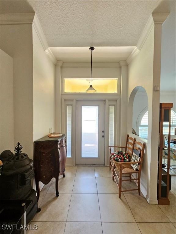3903 1st St SW, Lehigh Acres, FL 33976 - foyer with crown molding, plenty of natural light, arched walkways, light tile patterned floors, and a textured ceiling
