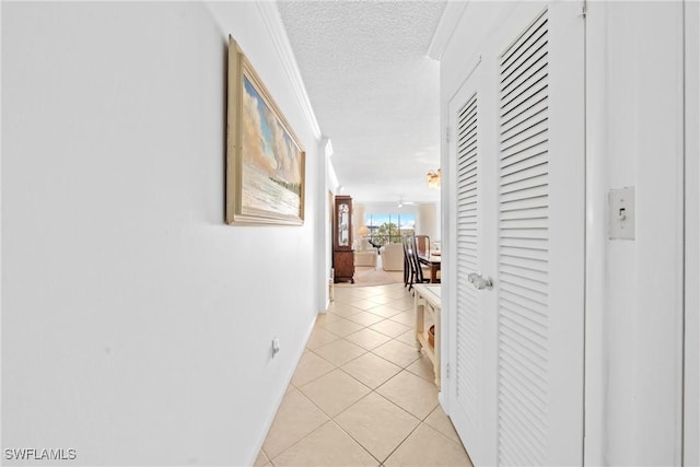 1977 Gulf Shore Blvd N Unit 302, Naples, FL 34102 - corridor featuring crown molding, a textured ceiling, baseboards, and light tile patterned floors