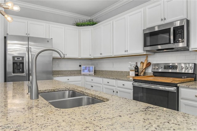 17326 Ashcomb Way, Estero, FL 33928 - kitchen with appliances with stainless steel finishes, white cabinetry, a sink, decorative backsplash, and ornamental molding