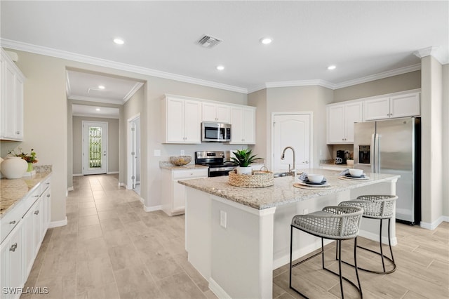 19694 Deming Ln, Estero, FL 33928 - kitchen with stainless steel appliances, a breakfast bar, white cabinets, ornamental molding, and recessed lighting