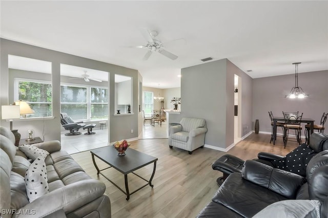 1340 Charleston Square Dr Unit 101, Naples, FL 34110 - living room with a ceiling fan, plenty of natural light, a chandelier, and light wood-style flooring