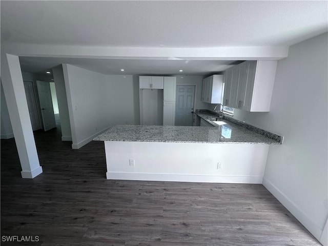 5981 Cubles Dr, Bokeelia, FL 33922 - kitchen with a peninsula, light stone counters, baseboards, and dark wood-type flooring