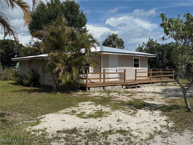 5981 Cubles Dr, Bokeelia, FL 33922 - view of front of property with a wooden deck, a metal roof, and a front lawn