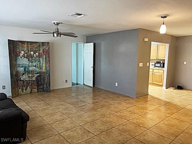 521 Pennview Ave, Lehigh Acres, FL 33936 - unfurnished living room with a ceiling fan, light tile patterned floors, and baseboards
