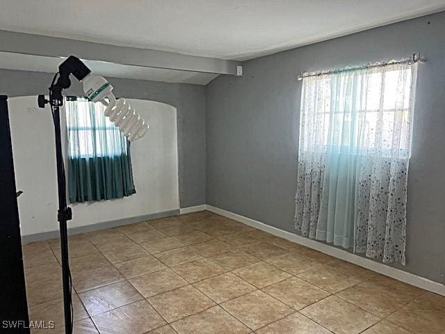 521 Pennview Ave, Lehigh Acres, FL 33936 - empty room featuring healthy amount of natural light, light tile patterned flooring, and arched walkways