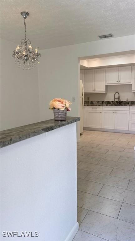 3916 SE 11th Pl Unit 503, Cape Coral, FL 33904 - kitchen with a sink, a chandelier, a textured ceiling, dark stone countertops, and white cabinets