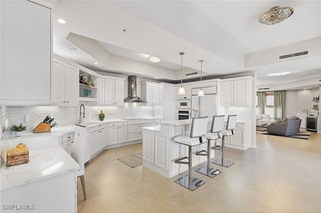 14270 Royal Harbour Ct Unit 920, Fort Myers, FL 33908 - kitchen with a breakfast bar, a tray ceiling, wall chimney exhaust hood, backsplash, and recessed lighting