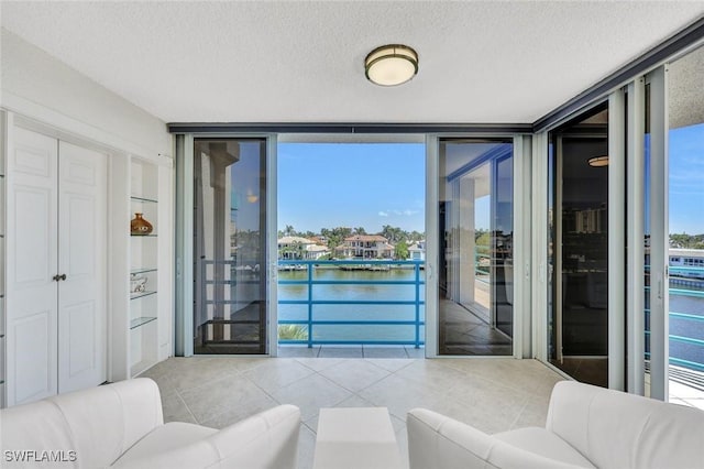 255 Park Shore Dr Unit 3-341, Naples, FL 34103 - living room with a wall of windows, a textured ceiling, a water view, and tile patterned floors