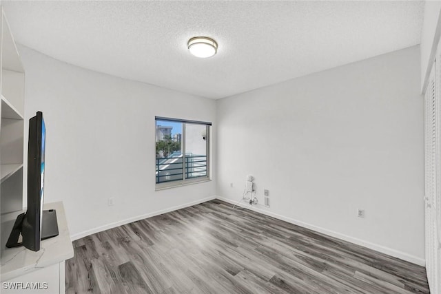 255 Park Shore Dr Unit 3-341, Naples, FL 34103 - unfurnished living room featuring wood finished floors, a textured ceiling, and baseboards