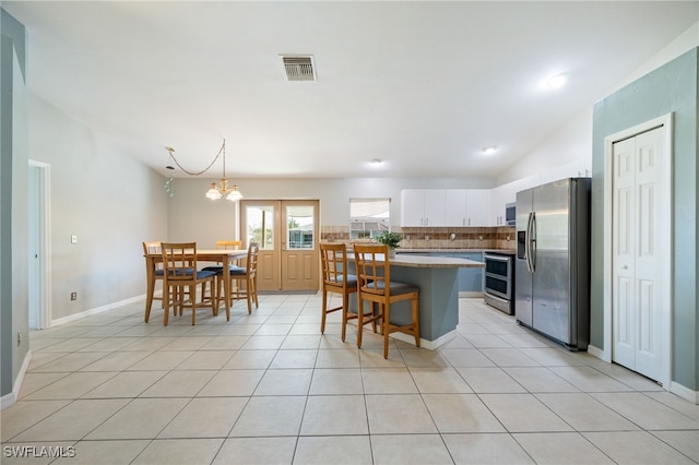 227 Manasota St, Fort Myers, FL 33913 - kitchen with appliances with stainless steel finishes, decorative backsplash, white cabinets, light tile patterned floors, and a breakfast bar area