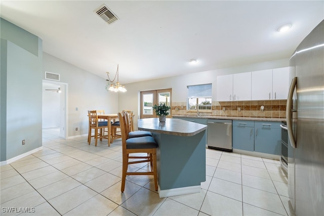 227 Manasota St, Fort Myers, FL 33913 - kitchen with appliances with stainless steel finishes, vaulted ceiling, backsplash, light tile patterned floors, and a center island