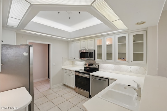 8380 Big Acorn Cir Unit 12A, Naples, FL 34119 - kitchen featuring appliances with stainless steel finishes, a sink, light tile patterned flooring, backsplash, and glass insert cabinets
