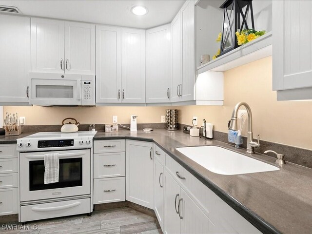 112 Marco Villas Dr Unit U2, Marco Island, FL 34145 - kitchen featuring white appliances, a sink, white cabinets, dark countertops, and recessed lighting