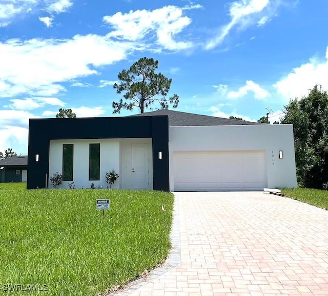 1218 Eclat St E, Lehigh Acres, FL 33974 - contemporary house with an attached garage, stucco siding, decorative driveway, and a front lawn