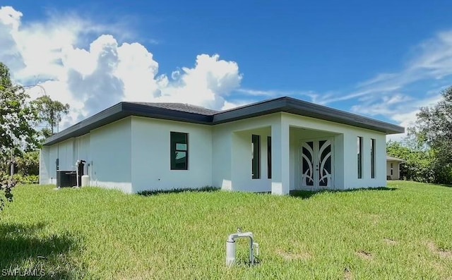 1218 Eclat St E, Lehigh Acres, FL 33974 - rear view of property with stucco siding and a yard