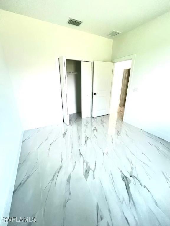 1218 Eclat St E, Lehigh Acres, FL 33974 - unfurnished bedroom with a closet and light marble finish flooring