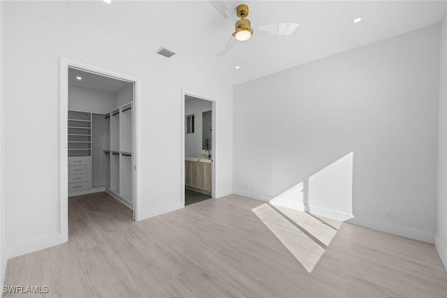 4440 15th Ave SW, Naples, FL 34116 - unfurnished bedroom with a spacious closet, light wood-style floors, a closet, ensuite bathroom, and ceiling fan