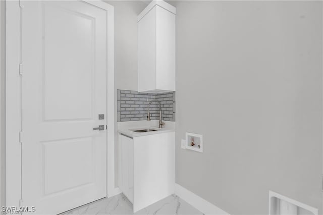 679 18th St NE, Naples, FL 34120 - laundry room with washer hookup, light marble finish floors, wet bar, baseboards, and cabinet space