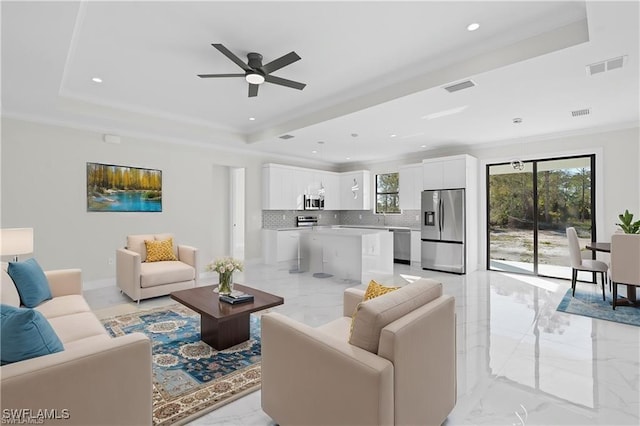 679 18th St NE, Naples, FL 34120 - living area featuring light marble finish flooring, healthy amount of natural light, a tray ceiling, a ceiling fan, and recessed lighting