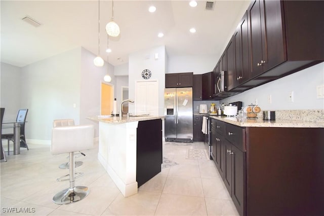 2640 36th Ave SE, Naples, FL 34117 - kitchen with stainless steel appliances, light stone countertops, light tile patterned floors, hanging light fixtures, and a center island with sink