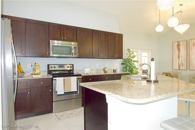 2640 36th Ave SE, Naples, FL 34117 - kitchen with stainless steel appliances, a sink, light stone counters, hanging light fixtures, and a center island with sink