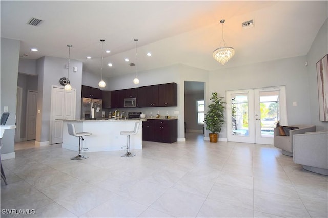 2640 36th Ave SE, Naples, FL 34117 - kitchen featuring appliances with stainless steel finishes, open floor plan, french doors, a kitchen bar, and a chandelier