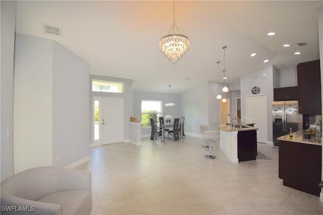 2640 36th Ave SE, Naples, FL 34117 - kitchen featuring stainless steel fridge with ice dispenser, a chandelier, a sink, an island with sink, and a breakfast bar