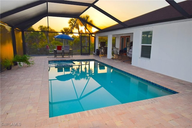 2640 36th Ave SE, Naples, FL 34117 - pool at dusk featuring a patio area, glass enclosure, and a pool with connected hot tub
