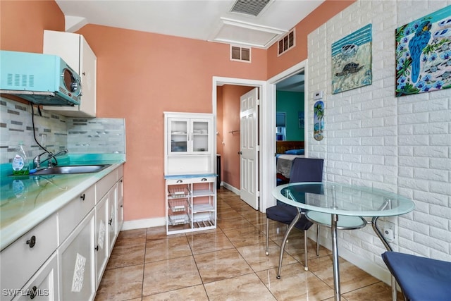 4617 Lombardy Ln, Naples, FL 34112 - kitchen featuring a sink, decorative backsplash, white cabinetry, light countertops, and light tile patterned flooring