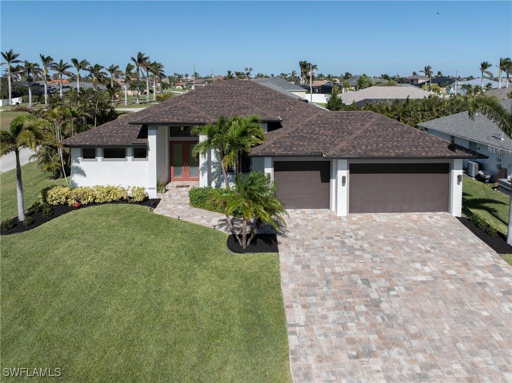 2711 SW 32nd St, Cape Coral, FL 33914 - prairie-style home with a shingled roof, a garage, a front lawn, and driveway