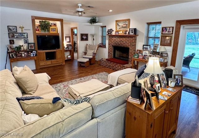 living area with wood finished floors, ceiling fan, and a fireplace