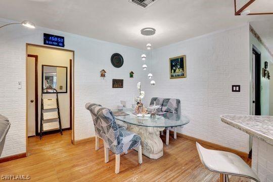 5251 Boxwood Way, Naples, FL 34116 - dining space with wood finished floors, brick wall, and baseboards