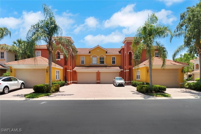 view of front of home featuring stucco siding, driveway, a tile roof, and a garage