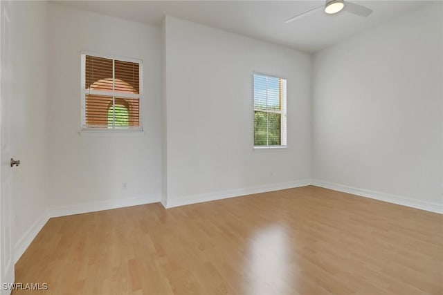 empty room featuring light wood-style floors, a ceiling fan, and baseboards
