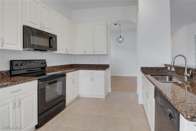 kitchen with black appliances, a sink, dark stone countertops, white cabinetry, and light tile patterned floors