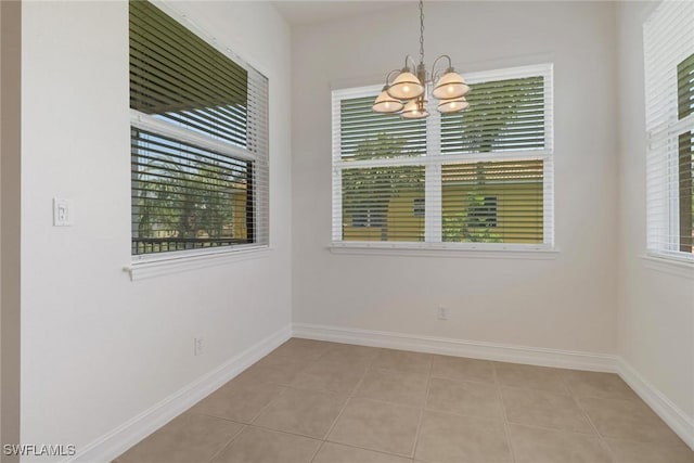 unfurnished dining area with a chandelier, light tile patterned floors, and baseboards