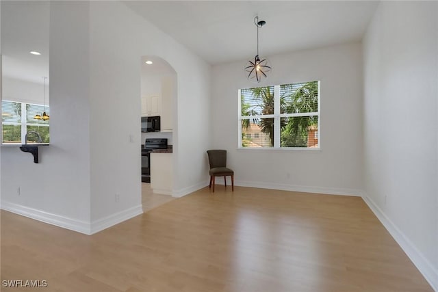 unfurnished living room featuring a chandelier, plenty of natural light, light wood-style floors, and recessed lighting