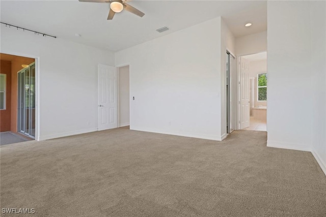 carpeted empty room with ceiling fan and baseboards