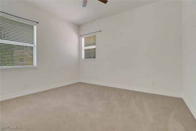 spare room with ceiling fan, light colored carpet, and baseboards